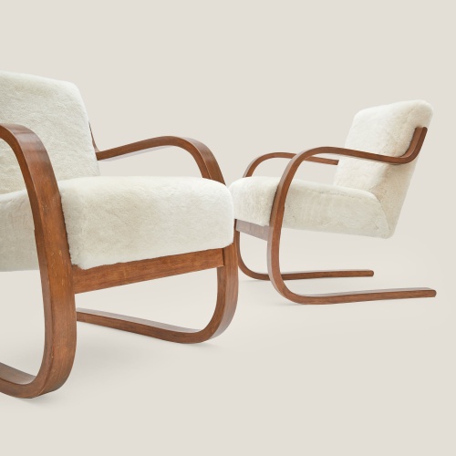 Des fauteuils design et résolument moderne en bois et peau lainée blanche.