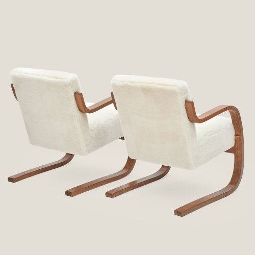 Des fauteuils cubiques et structure arrondie en bouleau et agneau velours blanc naturel, pour décorer votre salon.