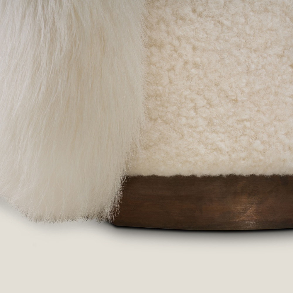 A sofa with brass legs and a structure upholstered in white sheepskin and finnraccoon.