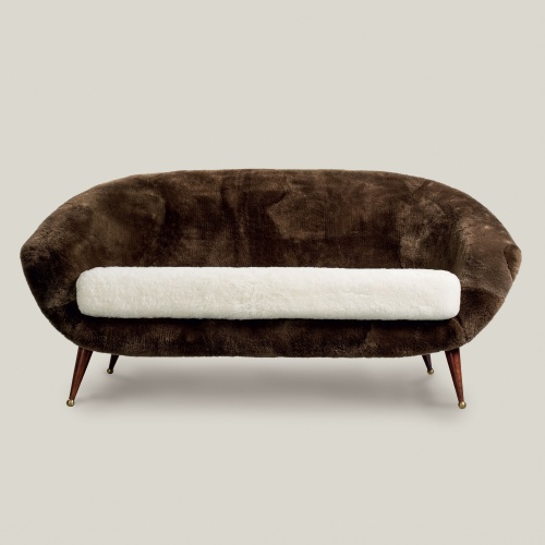 Front view of the Tellus Sofa in sheepskin with wooden and brass legs.