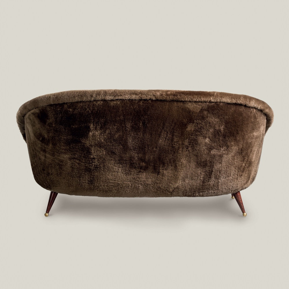 Back view of the Tellus Sofa in sheepskin with wooden and brass legs