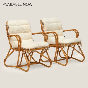 Pair of rattan armchairs with shearling cushions.