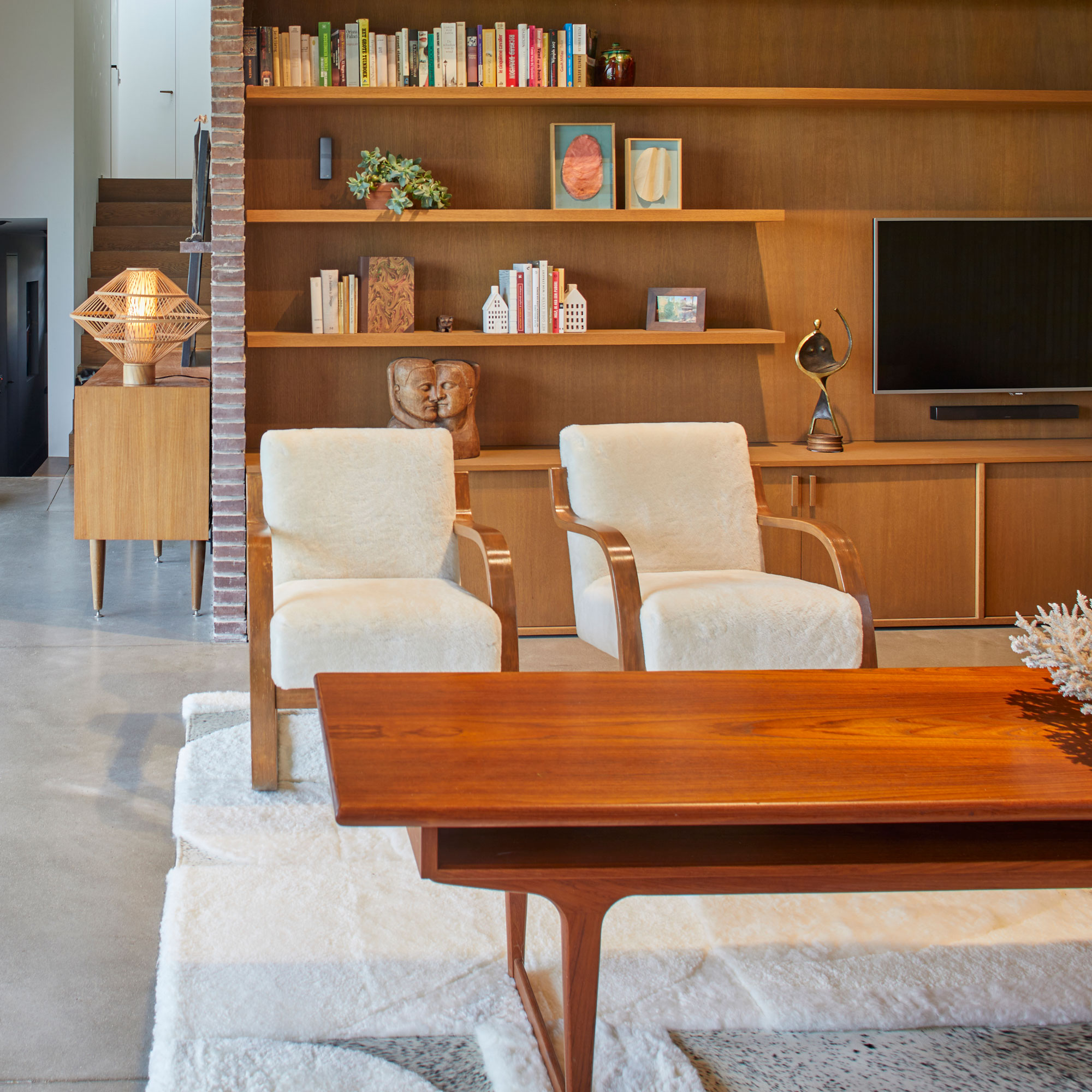 Two modern vintage armchairs on a large square white wool rug to decorate your living room.