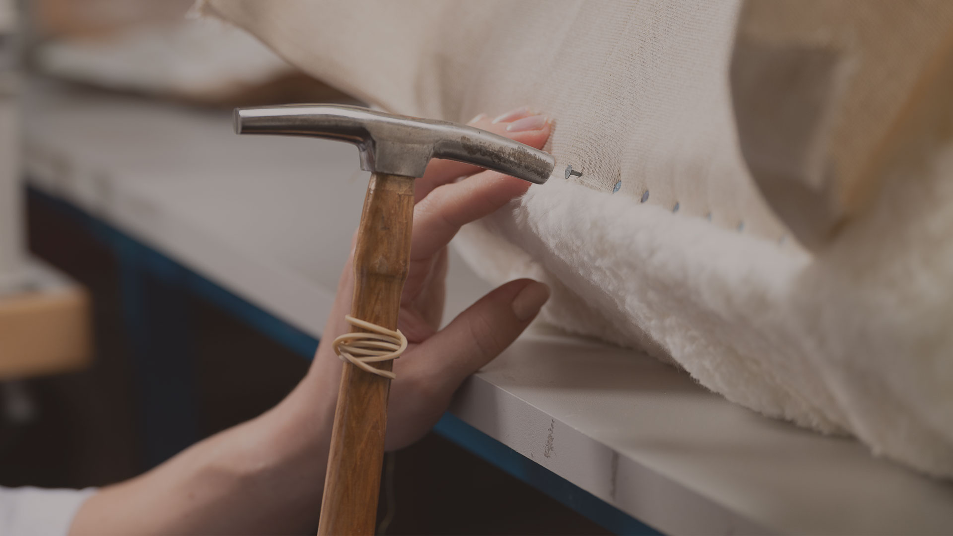 Artisan utilisant un marteau de tapissier sur une toile